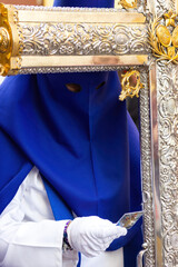 Penitent or Nazarene reading a prayer during the Holy Week procession.