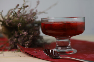 sweet delicious fragrant fruit jelly dessert with fresh strawberries in a transparent glass next to a vase with flowers. for labels, menus, splash screens, flyers, banners, and more