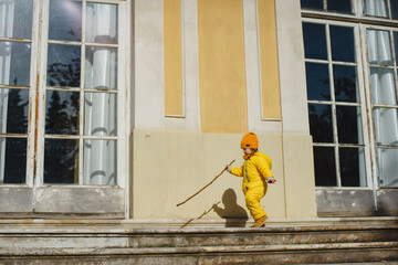 A child in a yellow jumpsuit and hat walks in a park with a fountain at Villa Durazzo in Genoa, Italy