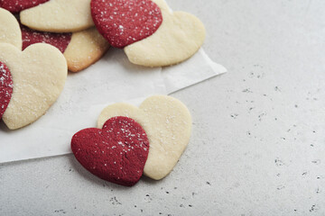 Obraz premium Valentines day cookies. Shortbread cookies inside sweet red heart with chocolate glaze on pink plate on grey background. Mothers day. Womans day. Sweet holidays baking. Valentines day card. Top view.