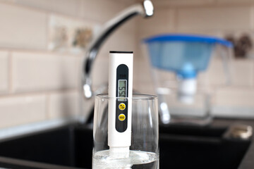 Tds meter for measuring water hardness is in the kitchen next to the sink, blue filter jug for water
