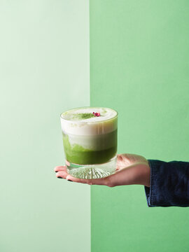 Crop person with glass of matcha latte