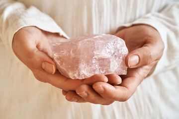 Woman in white shirt holding a rose quartz stone