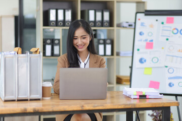 Attractive young Asian businesswoman working with laptop on her office desk.