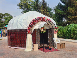 Asian wedding yurt, festively decorated with flowers and handmade carpets. - 569216767