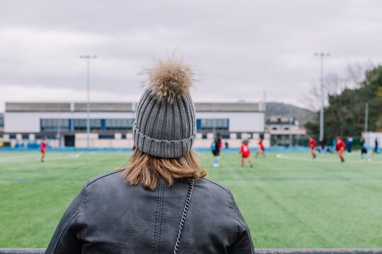 Unrecognizable woman in warm clothes watching football match