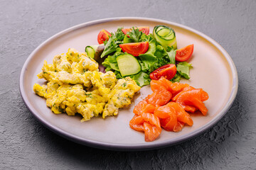 Scrambled eggs with salmon and tomato and cucumber salad