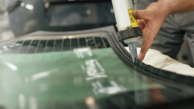 Skilled mechanic carefully adding glue to the windscreen of the car for replacement. High-quality 4k footage