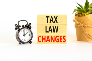 Tax law changes symbol. Concept words Tax law changes on wooden blocks on a beautiful white table white background. Black alarm clock. House plant. Business tax law changes concept. Copy space.