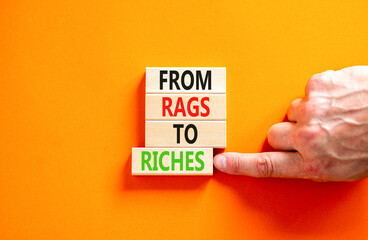 Rags or riches symbol. Concept words From rags to riches on wooden blocks. Beautiful orange table...