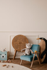 Minimalist composition of kid room interior with blue armchair, plush toys, wooden blocks, rattan...