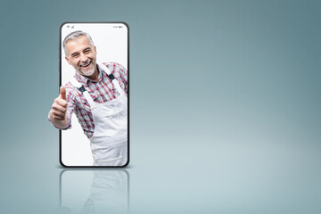 Confident painter and decorator  in a smartphone videocall and smiling, online  service concept © stokkete