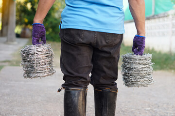 Closeup worker hand holds rolls of barbed wire. Concept, construction tool. Barbed wire is used for...