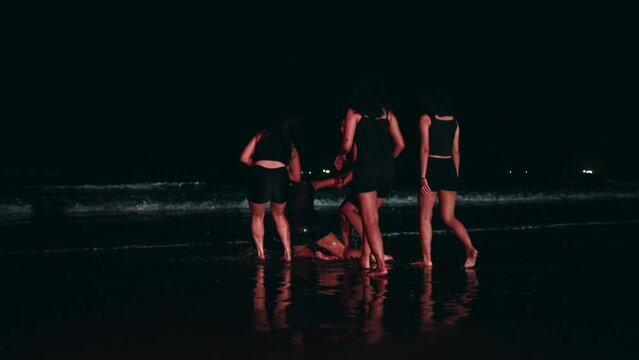 a group of Asian women bullied their friends by dragging them to the middle of a beach full of seawater until their bodies were wet