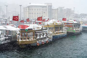 Fototapeta na wymiar Snow-covered fish restaurants on boats on a winter day in Istanbul, Turkey.