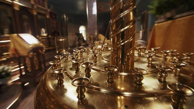 A gilded candle table in an orthodox church and a blurred view of the lectern in front of the iconostasis