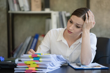 Businesswomen working in an office, young businesswomen stressed from work overload with a lot of files on the desk.