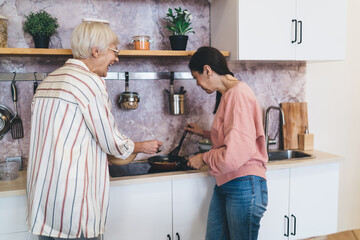Cheerful diverse girlfriends preparing meal together in kitchen