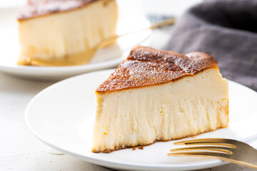 明るいテーブルにバスクチーズケーキと金色のフォーク