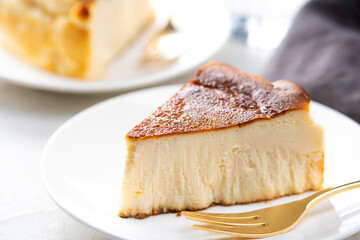 明るいテーブルにバスクチーズケーキと金色のフォーク