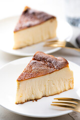 明るいテーブルにバスクチーズケーキと金色のフォーク