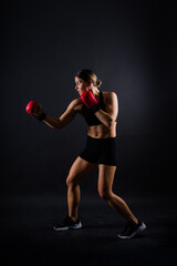 Strong sportswoman in boxing gloves prepared high kick. Isolated on white, red, yellow background