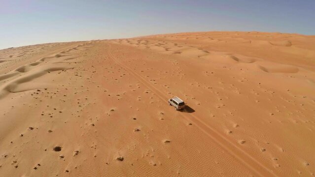 Cinematic aerial top view of a car driving in the desert