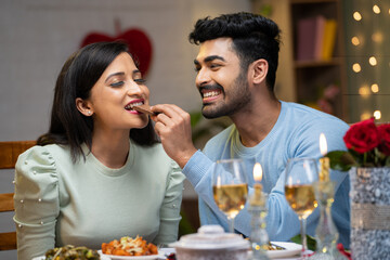 Happy Girl taking bite of chocolate from boyfriend during valentines day dating - concept of...