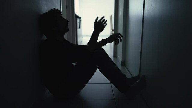 One anxious depressed man in despair sitting at home in the dark. Person suffering from mental illness alone in corridor feeling shame and regret