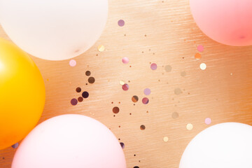 Golden background with pink, gold and white air balloons and confetti, design element