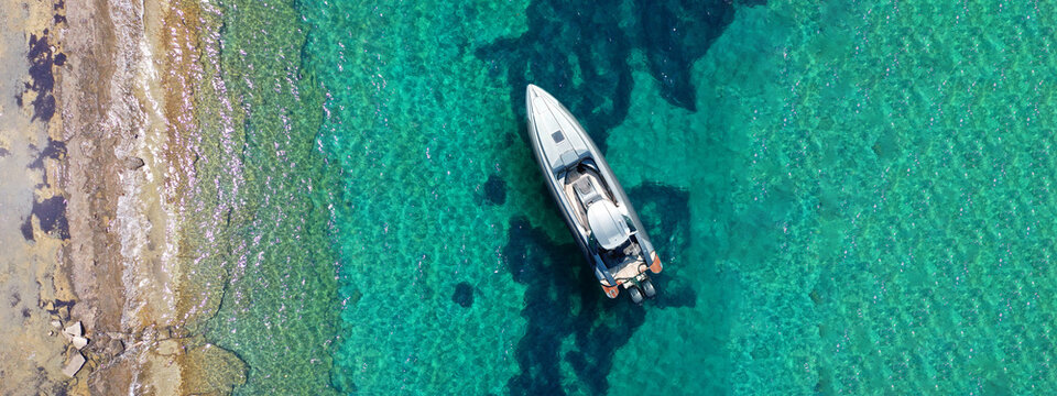 Aerial drone ultra wide top down photo with copy space of inflatable speed boat anchored in tropical exotic island