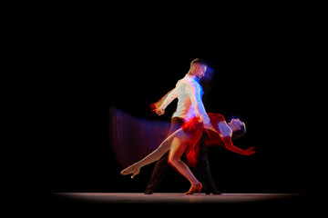 Man and woman, professional dancers performing ballroom, tango over black background with mixed...
