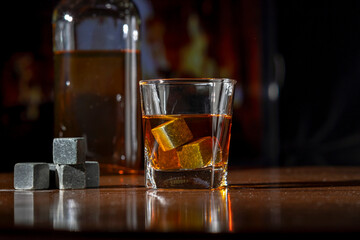 A glass of whiskey on a dark background. Whiskey cooling stones on the table.