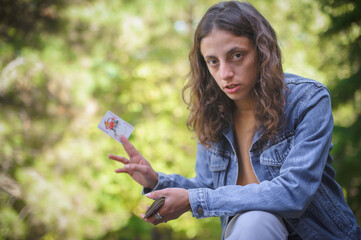 Playing cards in the spring garden. A woman plays cards and holds a joker in her hand.