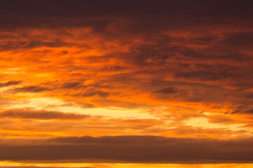 Background image with clouds in extreme colors of a sunset. The sky seems to burn