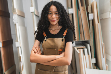 Confident teenager carpenter African American woman working with wood sheet at wood factory	