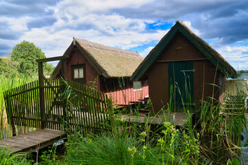Fototapeta na wymiar Fishing lodge on the lake near Krakow on the lake. Inland fishing. Vine roof on the house