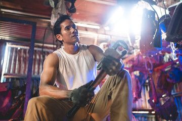 Portrait of a confident Asian male mechanic holding wrench at garage, Auto mechanic standing against a car in a repair garage for using in business of car, expertise mechanic working in automobile
