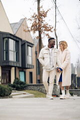 Obraz premium Young interracial couple holds each other hand and walks on street.