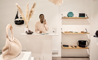 Young African entrepreneur talking on a phone in her boutique