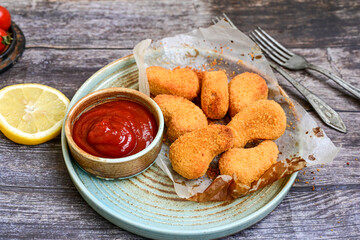 
 Crispy oven baked  chicken nuggets and ketchup. Breaded chicken fillets  with chilly peppers and fresh basi on wooden rustic background