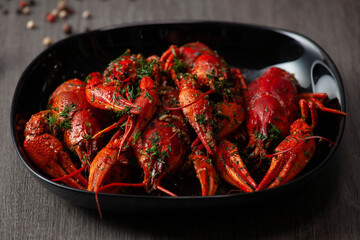 Many pickled boiled crawfish on a black plate