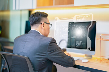 Businessman looking at a computer monitor during his working day in the office. Business ans success concept