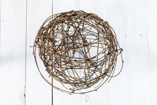 circular ball of dried vines on a white wooden background
