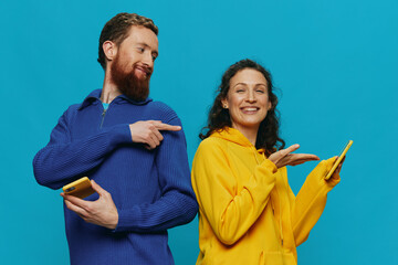 Woman and man cheerful couple with phones in their hands crooked smile cheerful, on blue background. The concept of real family relationships, talking on the phone, work online.