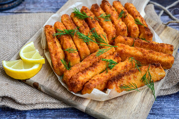 Close up of   Crispy breaded  deep fried fish fingers with breadcrumbs served  with remoulade sauce and  lemon Cod Fish Nuggets on rustic wood table background