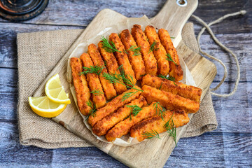 Close up of   Crispy breaded  deep fried fish fingers with breadcrumbs served  with remoulade sauce and  lemon Cod Fish Nuggets on rustic wood table background