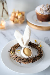 Festive Easter table setting with Easter bunny made of linen napkin and yellow egg