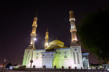 The Al Farooq Omar Bin Al Khattab Mosque, known as Blue Mosque in Dubai, United Arab Emirates, Ottoman style architecture, night view with illuminations. - obrazy, fototapety, plakaty