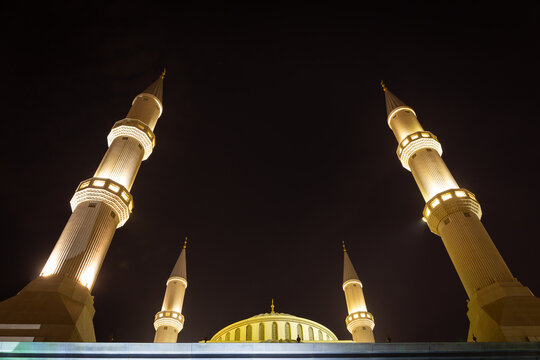 The Al Farooq Omar Bin Al Khattab Mosque (Blue Mosque) minarets and dome, Dubai, UAE. Ottoman style architecture, night symmetrical view with illuminations, dark sky background, copy space.